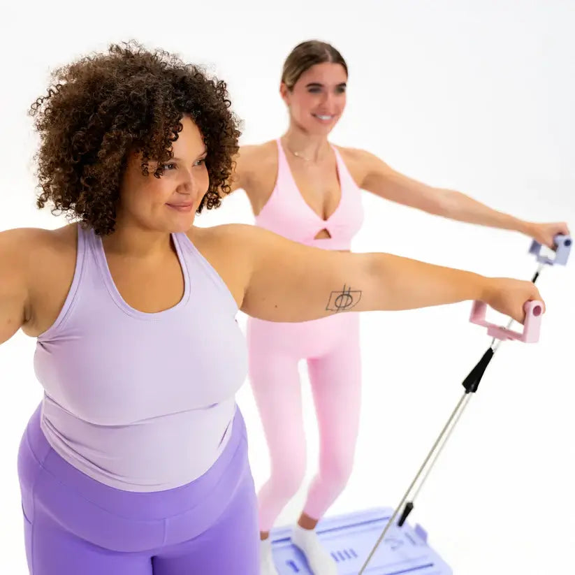 Two women using a Pilates reformer for a home workout, focusing on strength, flexibility, and core stability.